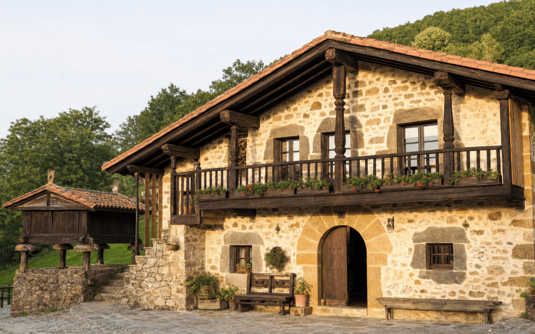 Caserío vasco tradicional con elementos arquitectónicos típicos: balcón de madera, mampostería y teja